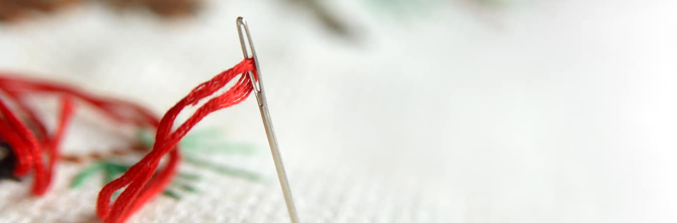 Needle in canvas with red thread for embroidery